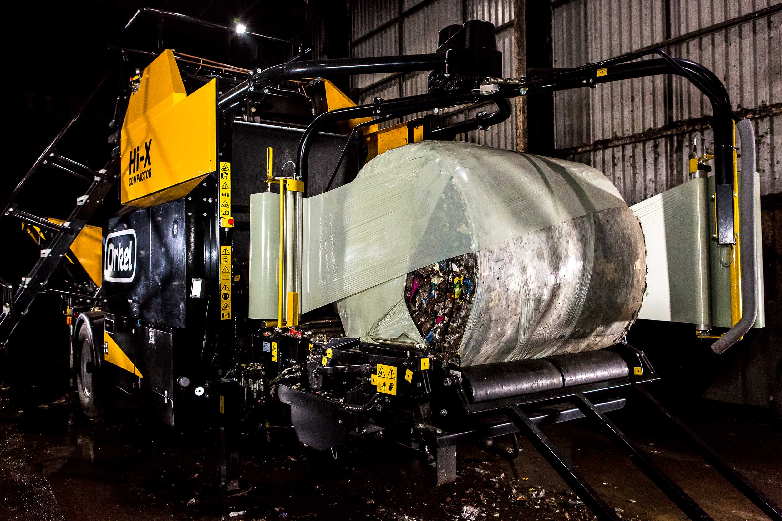 Orkel compactor in a dark warehouse, baling waste