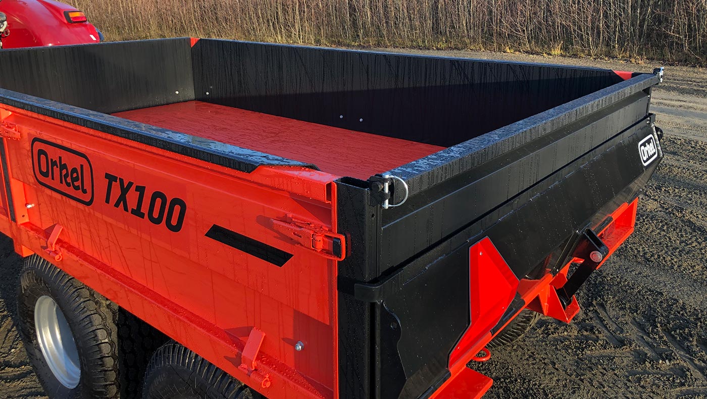 Detaljebilde av rød Orkel TX100 traktorhenger stående ute med litt regndråper på seg