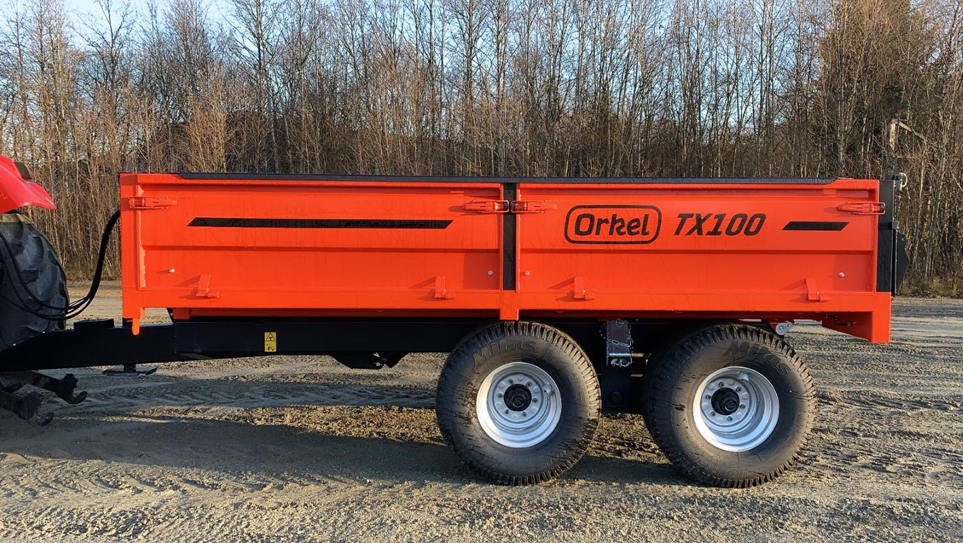 Rød Orkel TX100 traktorhenger stående ute med litt regndråper på seg