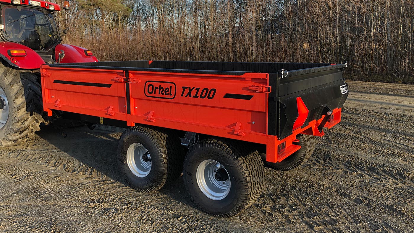 Rød Orkel TX100 traktorhenger stående ute med litt regndråper på seg