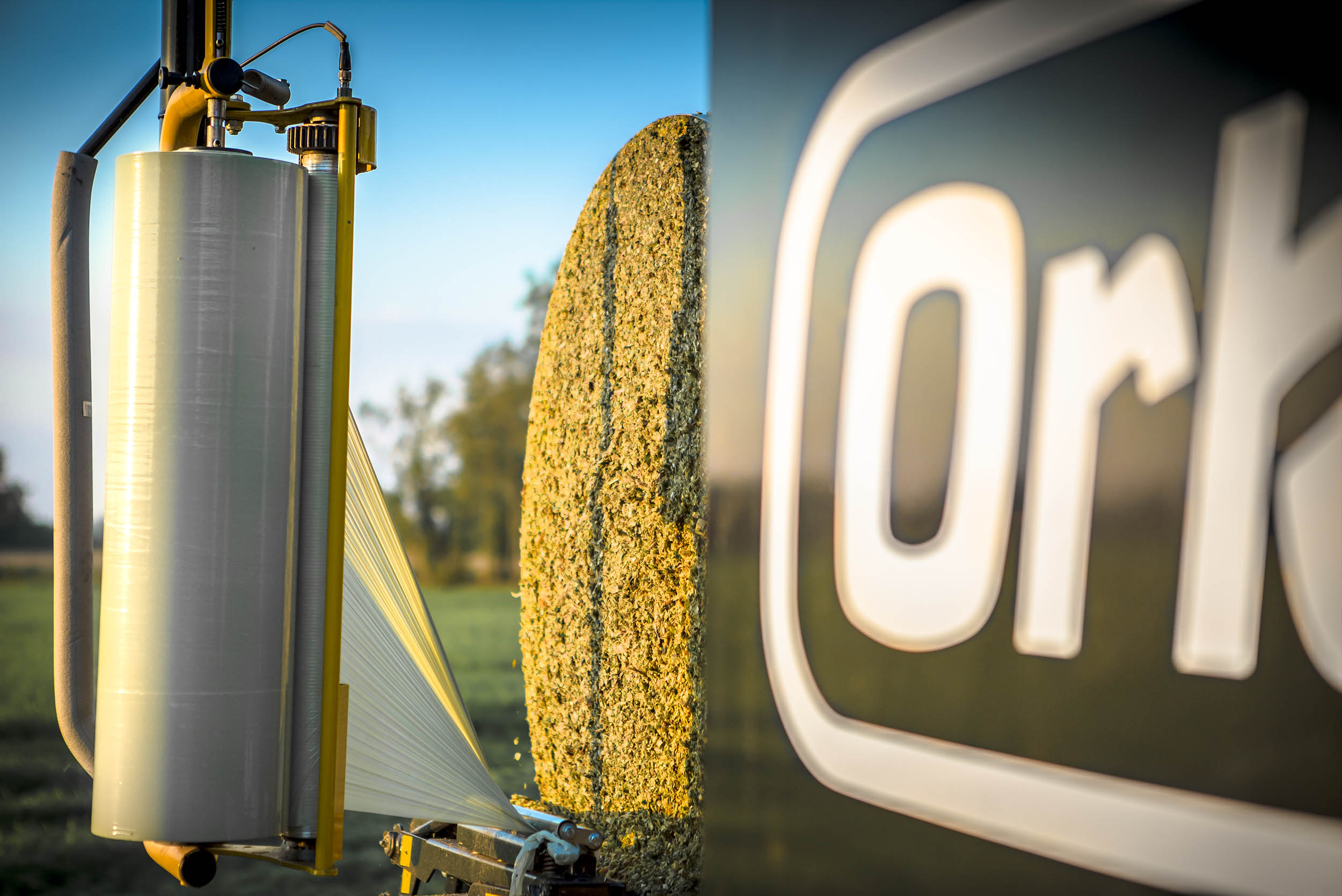 Closeup on the wrapping table of a Orkel compactor, with a maize bale ready for wrapping, sunny weather