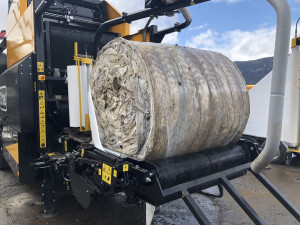 The image shows a waste bale containing agricultural plastic being wrapped in plastic on an orkel compactor