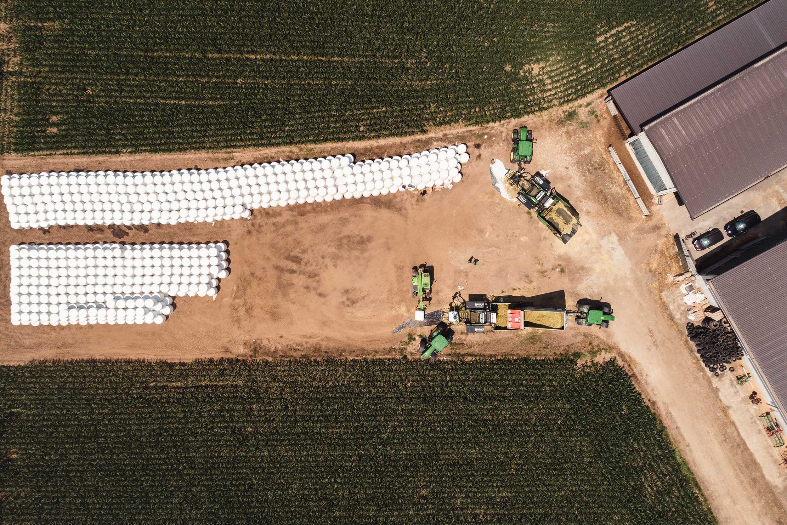 Maize field, stacks of round bales and Orkel compactors seen from above