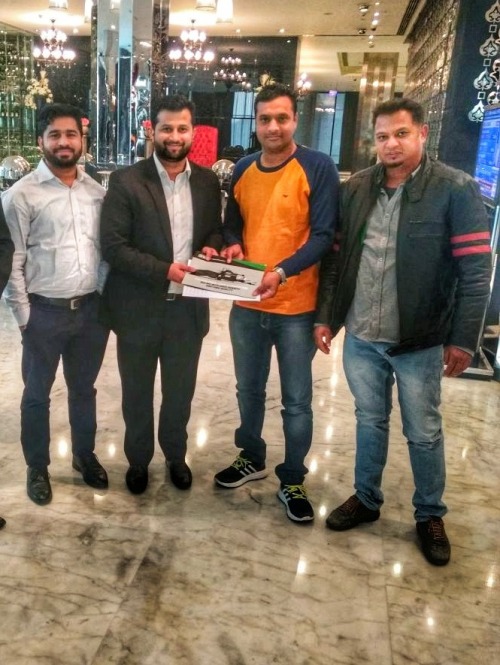 Four guys in a hotel lobby holding a Orkel brochure